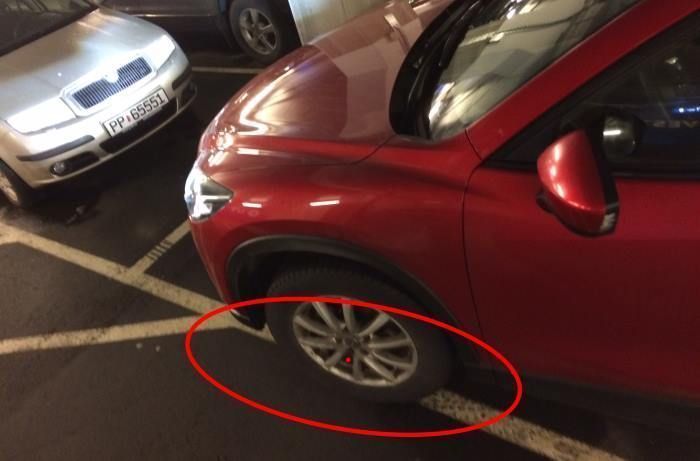 Rød bil parkerer på streken i parkeringshus.