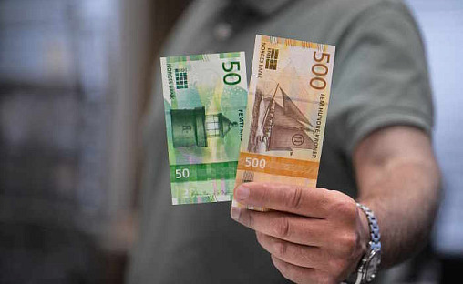 Mann holder opp pengesedler.
