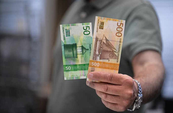 Mann holder opp pengesedler.